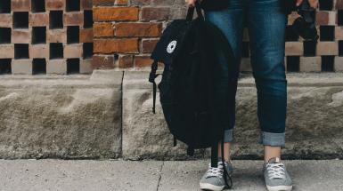Una giovane ragazza con in mano il suo zaino